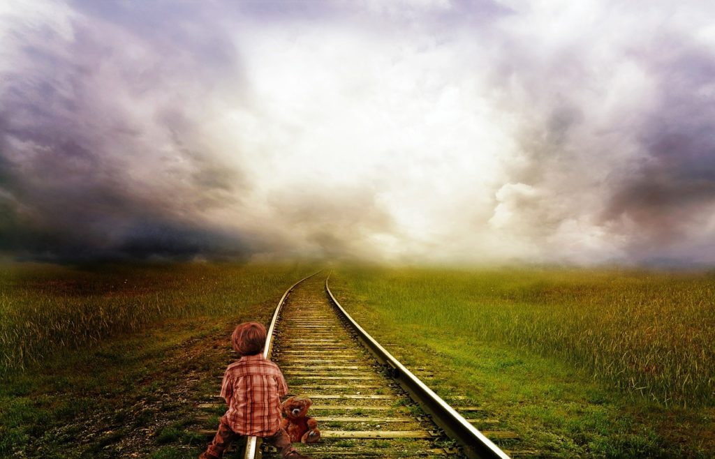 child sitting on railway tracks